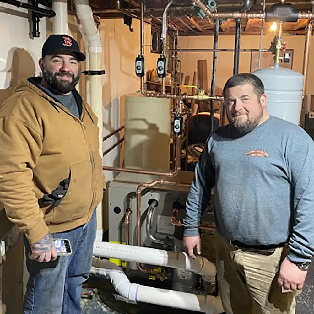 two service techs in basement of residential home in Providence, RI.
