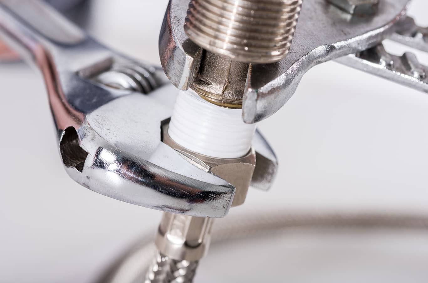 Wrenches tightening connectors on pipe in bathroom