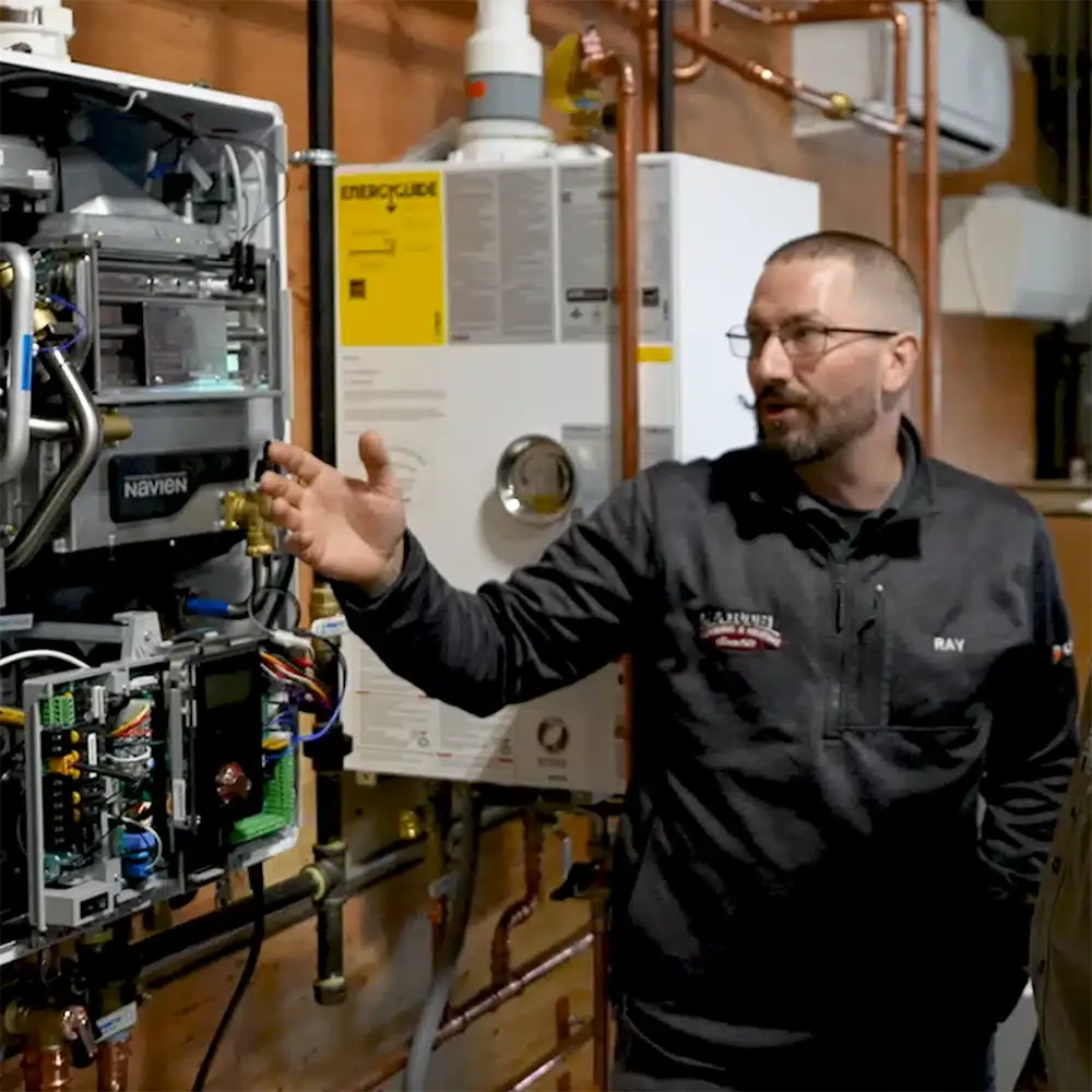 Martel plumbing and heating specialist pointing to a water heater.